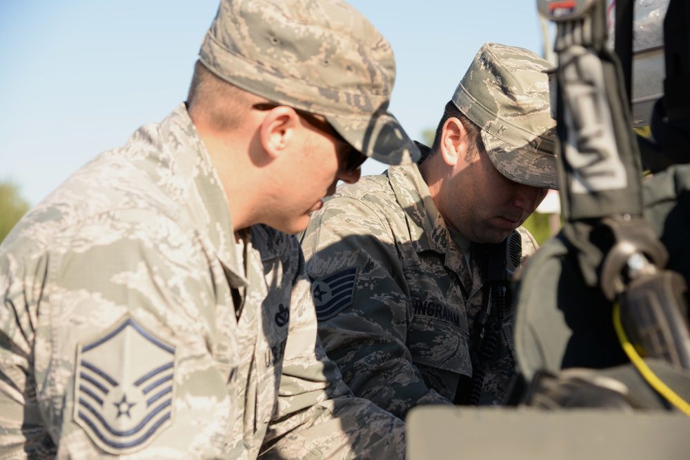 Two firefighters in uniform consult a spill response checklist together, focused on the document, with response equipment visible in the foreground.